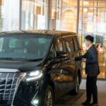 Chauffeur standing by a black car