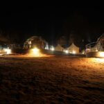 Dome tents lit up at night in a desert camp