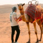 Man standing with a camel in the desert